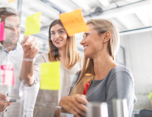 Business people meeting at office and use post it notes to share idea. Brainstorming concept. Sticky note on glass wall.